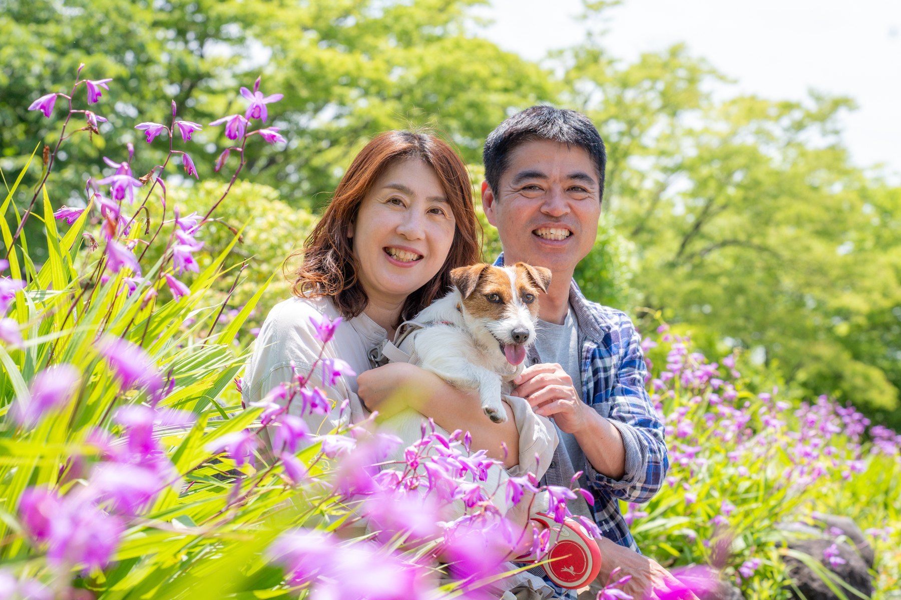 花畑で愛犬と笑顔を見せる家族